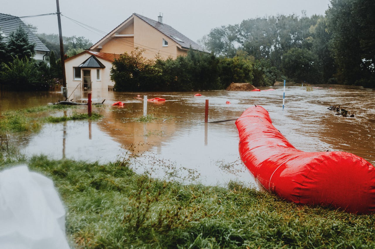 Home Flooded residential area protected by red flood barriers, showing severe weather impact.
